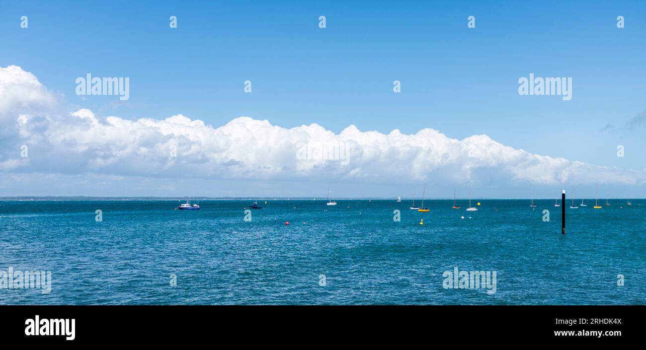 Des nuages blancs se sont réunis le long de l'horizon à Yarmouth, île de Wight, Angleterre, Royaume-Uni contrastant avec la mer bleue riche. Banque D'Images