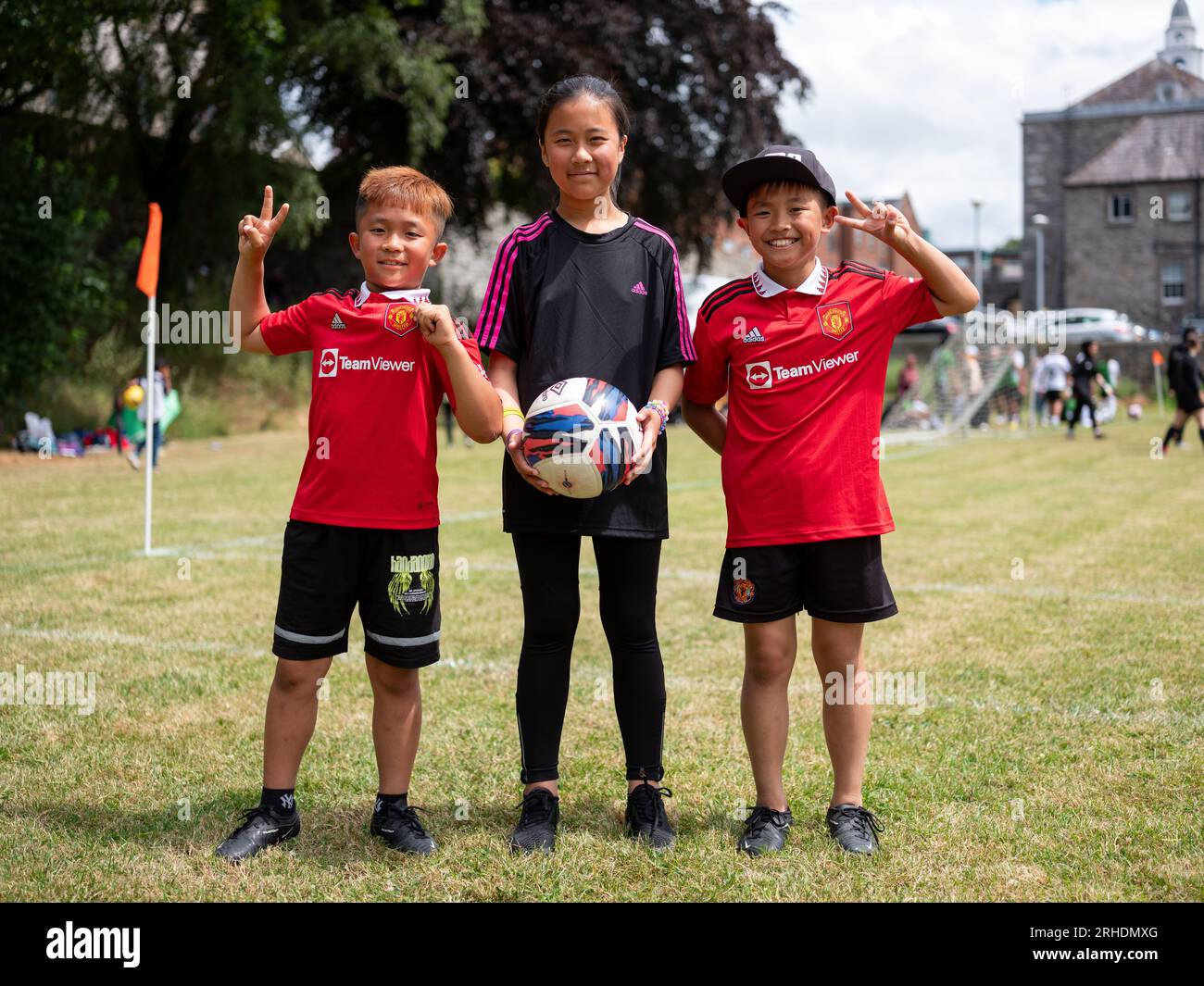 Trois jeunes enfants souriants portant des tenues de football Manchester United. Banque D'Images