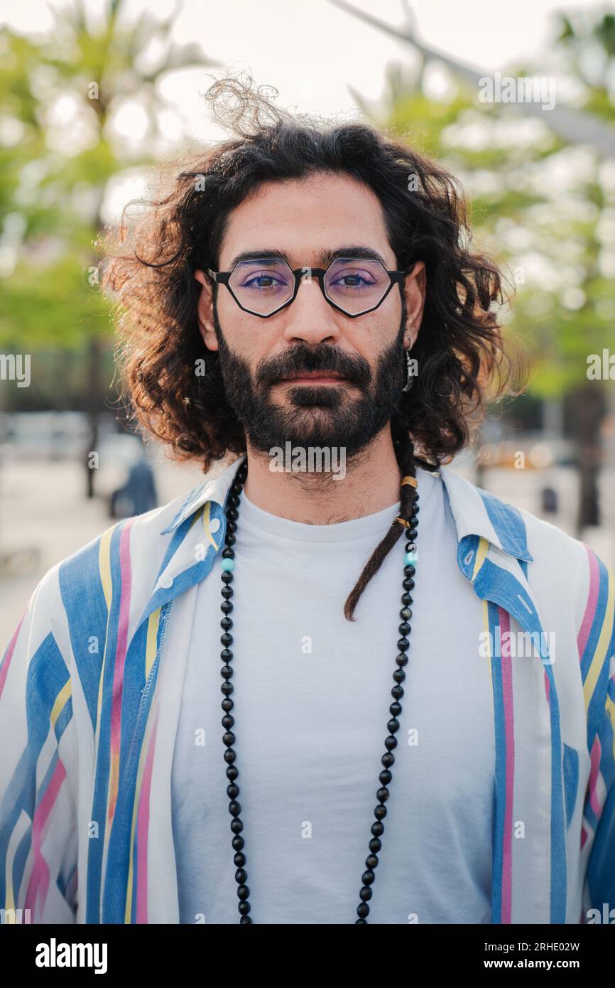 Portrait vertical d'un jeune homme adulte regardant la caméra avec une expression sérieuse et confiante sur son visage, portant des vêtements décontractés, debout à l'extérieur. Vue de face d'un homme barbu à attitude pensive. Photo de haute qualité Banque D'Images