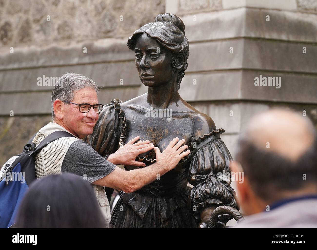 Les gens posent pour des photos avec l'emblématique statue de Molly Malone dans le centre-ville de Dublin après qu'elle a été vandalisée avec de la peinture noire sur son devant. La statue de la figure semi-historique et semi-légendaire est une destination touristique populaire. Date de la photo : mercredi 16 août 2023. Banque D'Images