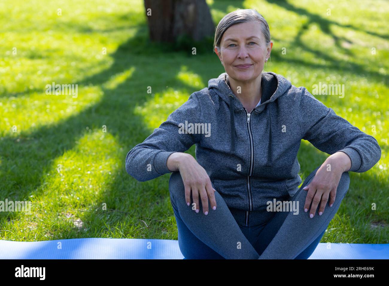 Femme en vêtements de sport reposant sur le tapis de yoga après le cours Banque D'Images