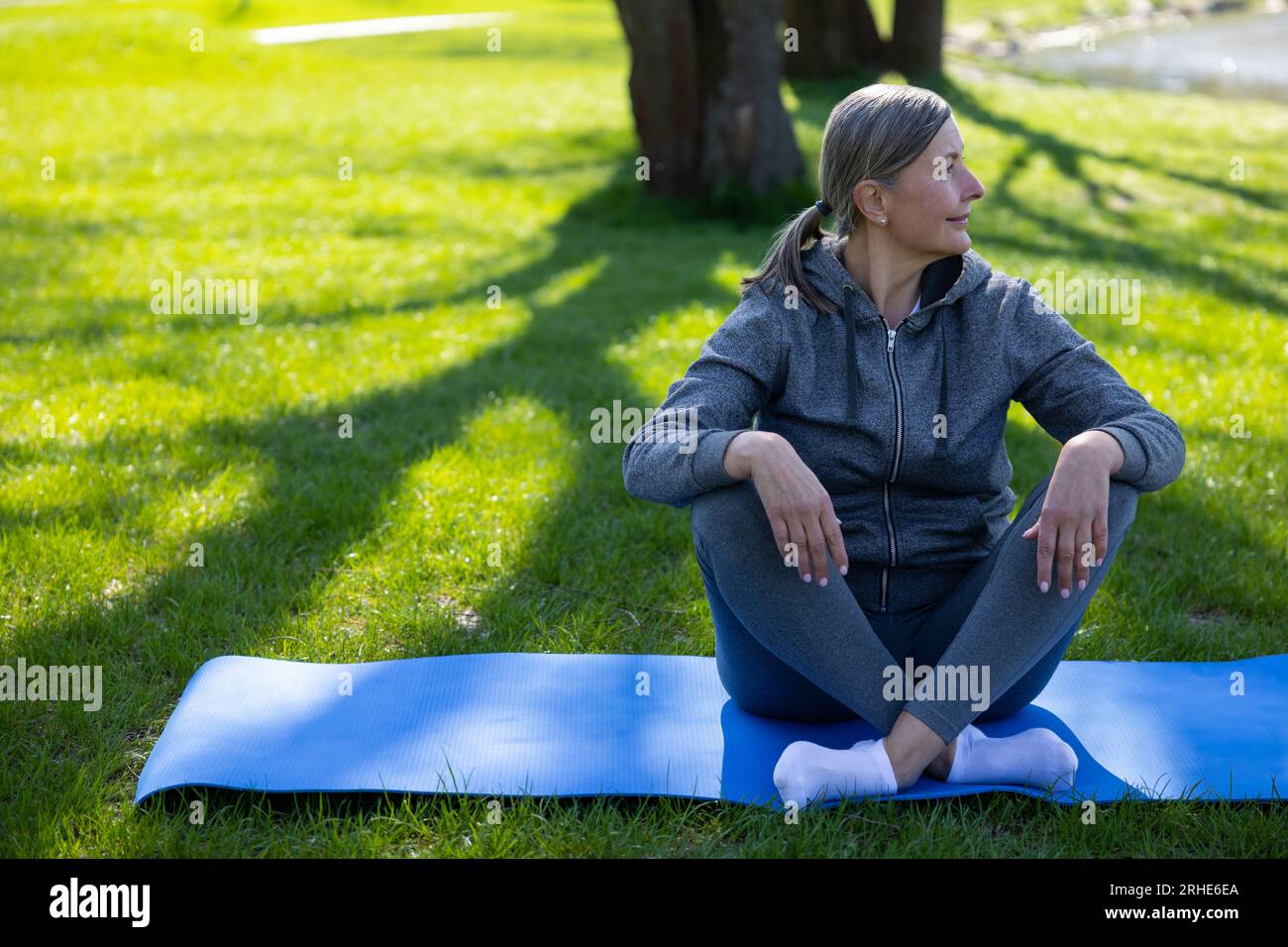 Femme en vêtements de sport reposant sur le tapis de yoga après le cours Banque D'Images