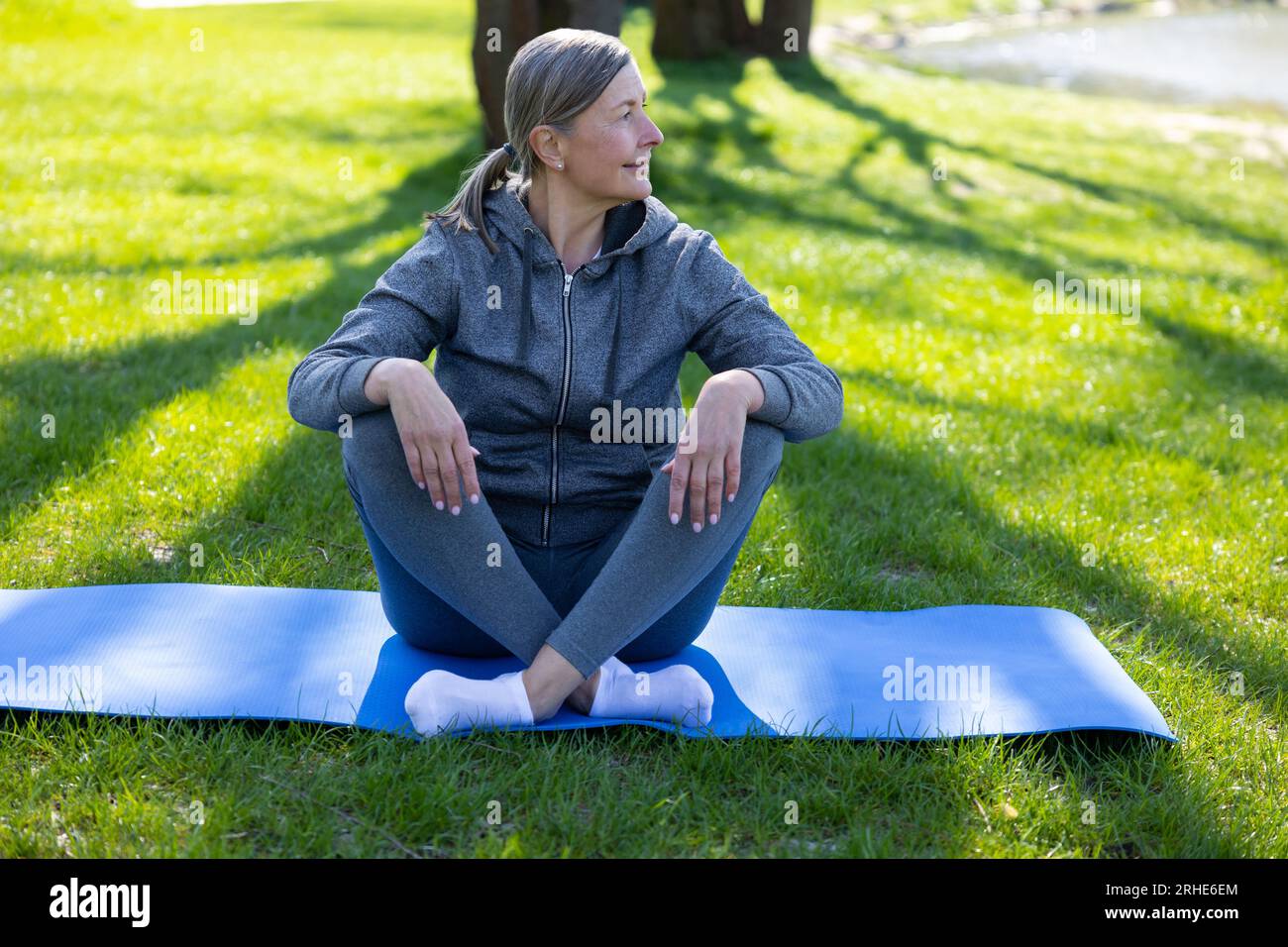 Femme en vêtements de sport reposant sur le tapis de yoga après le cours Banque D'Images