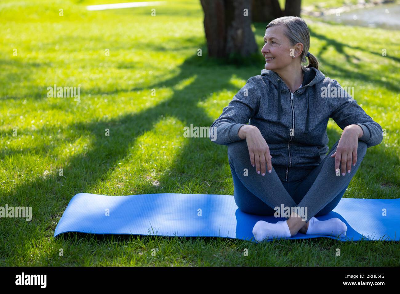 Femme en vêtements de sport reposant sur le tapis de yoga après le cours Banque D'Images
