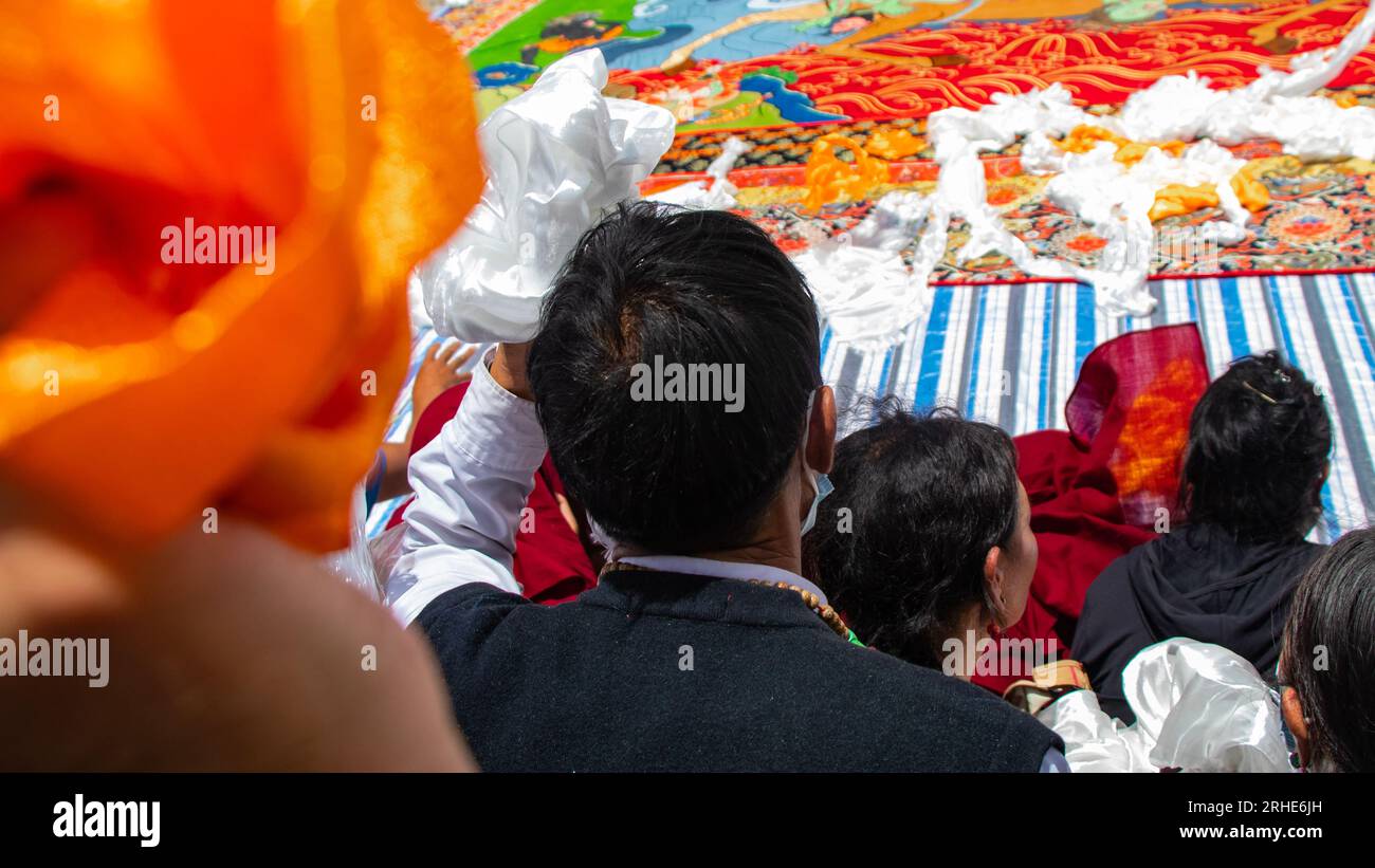 Lhassa, région autonome du Tibet en Chine. 16 août 2023. Les gens jettent des hadas, ou des foulards de soie utilisés par les Tibétains pour exprimer leur respect et leurs salutations, lors d'une immense peinture Thangka lors de la cérémonie du « soleil du Bouddha » au monastère de Drepung à Lhassa, dans la région autonome du Tibet du sud-ouest de la Chine, le 16 août 2023. Les célébrations pour le traditionnel festival Lhassa Shoton (banquet de yaourt) ont commencé à Lhassa mercredi. Crédit : He Bingjie/Xinhua/Alamy Live News Banque D'Images