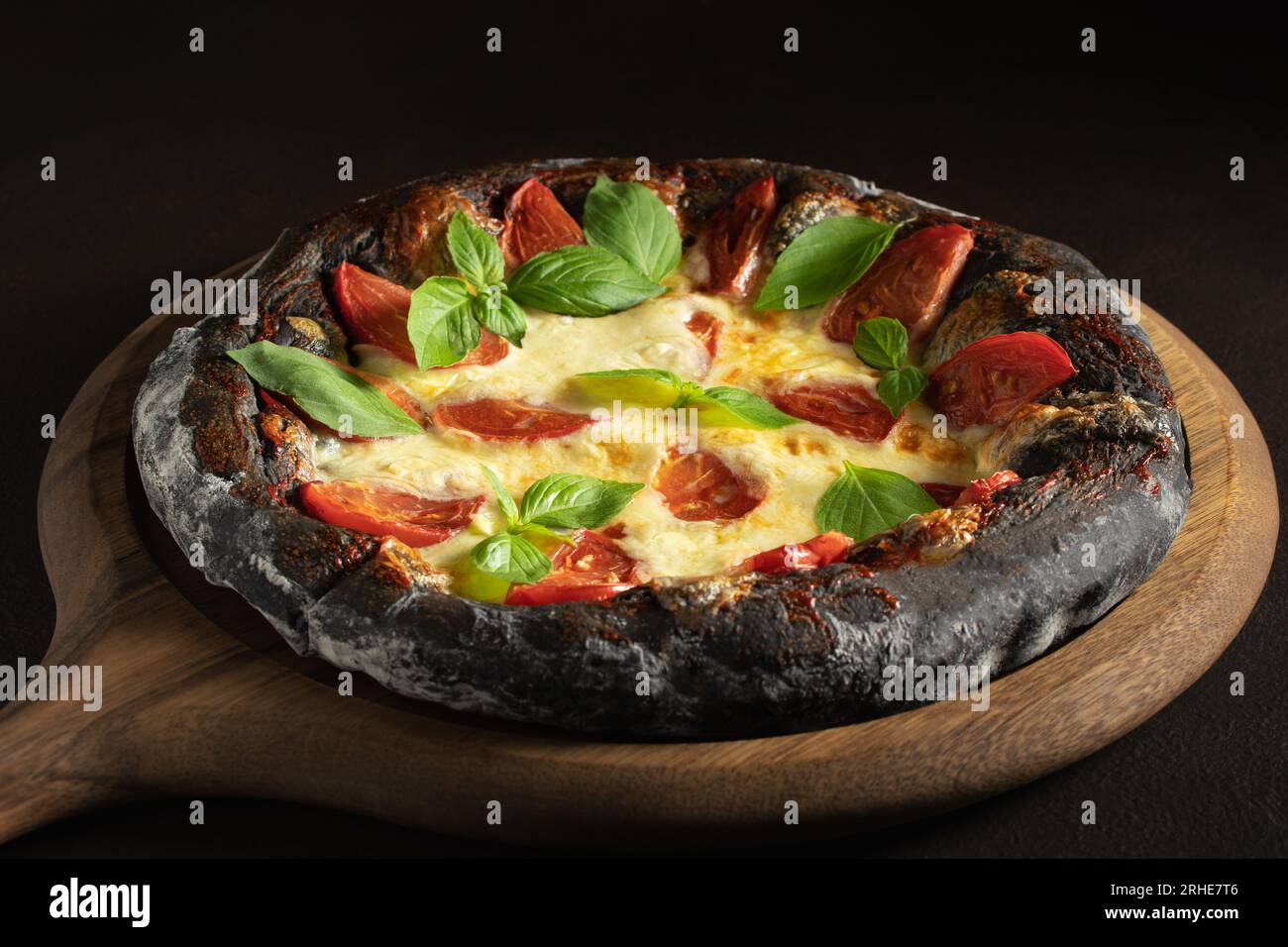 Pizza noire margarita avec tomates, mozzarella et basilic. Pâte avec de la poudre de charbon de bambou saine. Banque D'Images