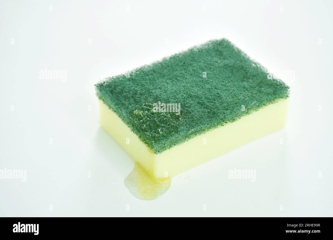 éponge de gommage jaune et vert avec lavage liquide sur fond blanc Banque D'Images