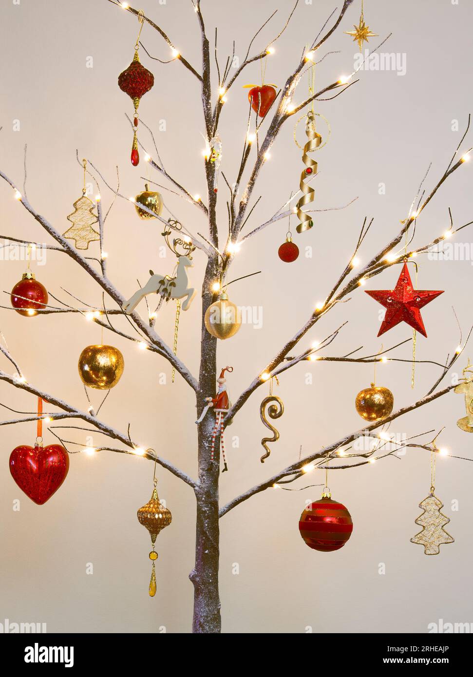 Décorations de Noël en rouge et or traditionnel accrochées à un arbre perruque moderne avec effet neige Banque D'Images