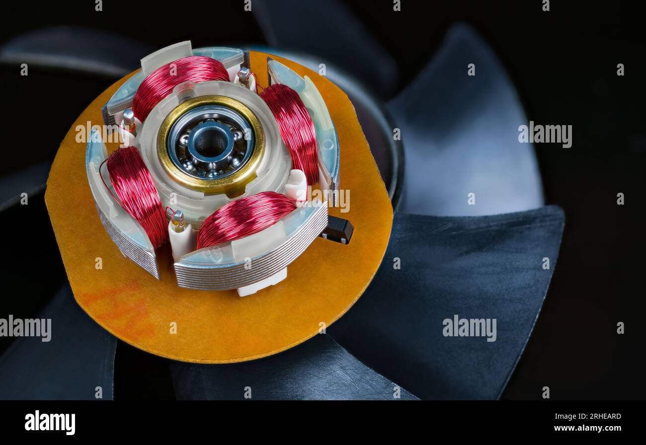 Gros plan d'un stator de moteur électrique avec bobines électroniques et roulement à billes. Enroulement du fil de cuivre rouge du moteur électrique du ventilateur de l'ordinateur sur les ailettes en plastique du rotor. Banque D'Images