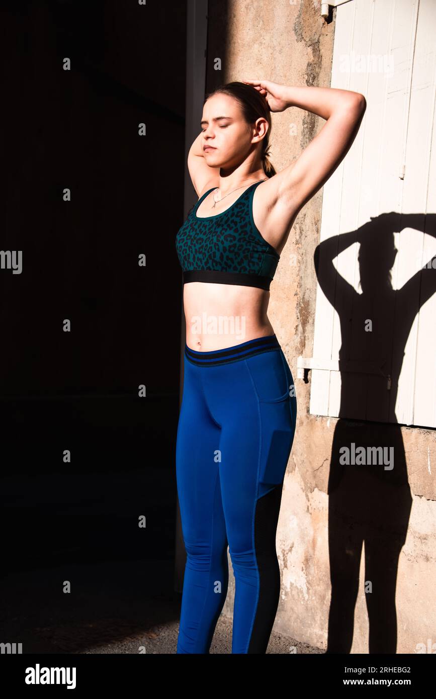 jeune femme s'étirant dans la lumière tôt le matin dans la petite rue, habillée en vêtements de sport .concept de sport et de fitness . Banque D'Images