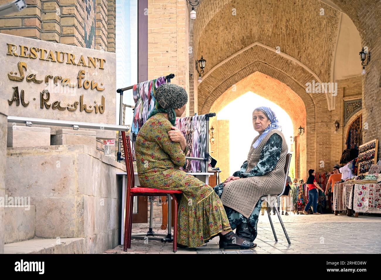 Deux femmes ouzbèkes assises et parlant dans les rues de la vieille ville de Boukhara, Ouzbékistan Banque D'Images
