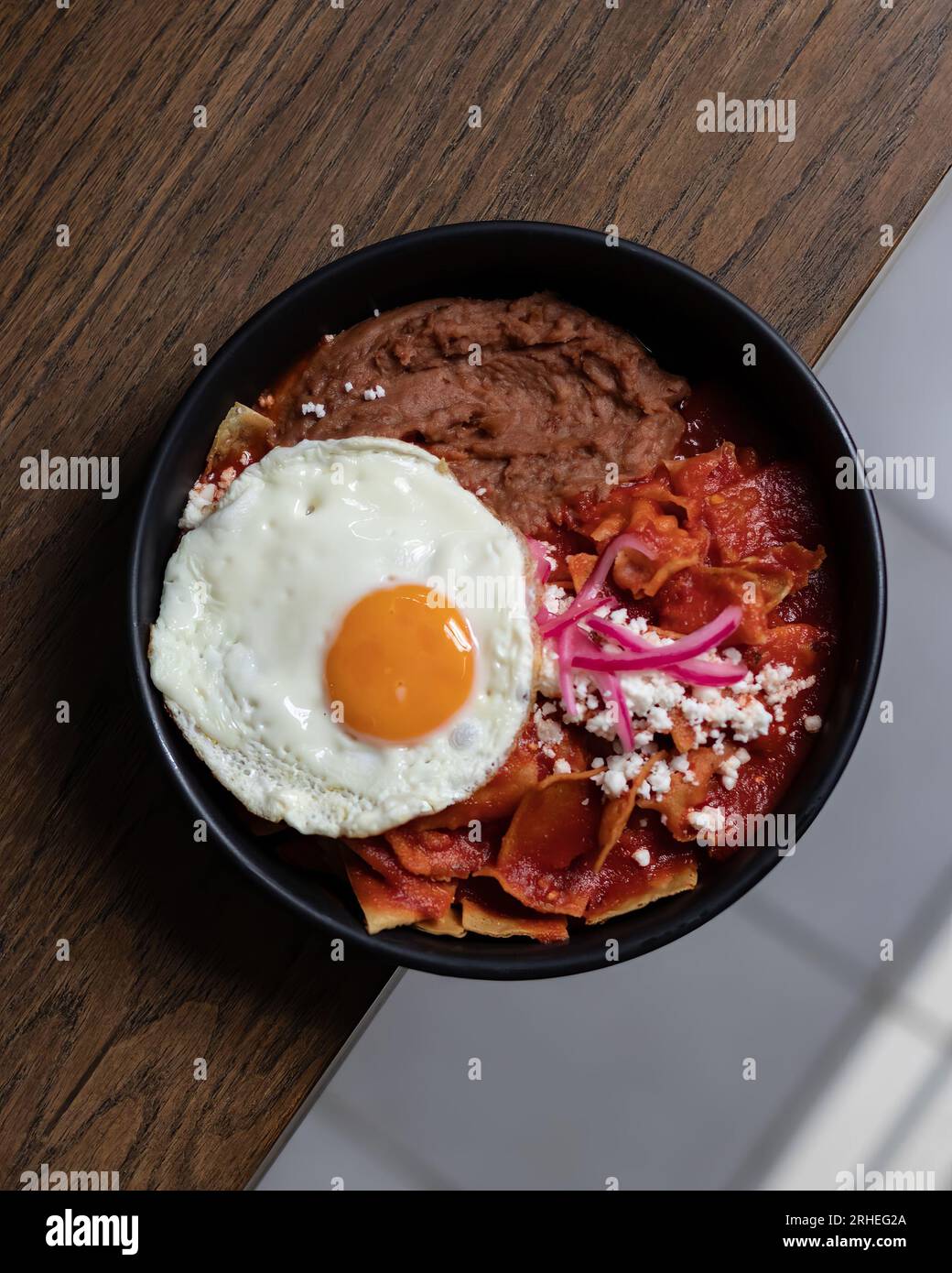 Petit déjeuner copieux avec œufs brouillés, bacon, haricots, tomates cerises, pain maison, jus d'orange sur un comptoir en béton. Concept petit déjeuner anglais. Banque D'Images