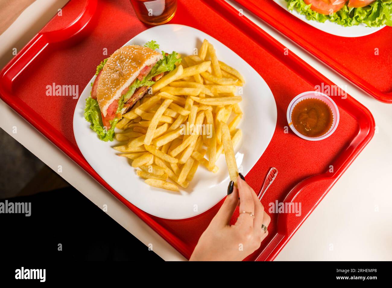 mains cueillant des frites dans l'assiette avec sandwich à la table de restaurant fastfood, vue de dessus Banque D'Images mains cueillant des frites dans l'assiette avec sandwich à la table de restaurant fastfood, vue de dessus Banque D'Images