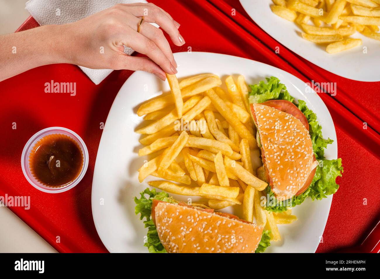 mains cueillant des frites dans l'assiette avec sandwich à la table de restaurant fastfood, vue de dessus Banque D'Images mains cueillant des frites dans l'assiette avec sandwich à la table de restaurant fastfood, vue de dessus Banque D'Images