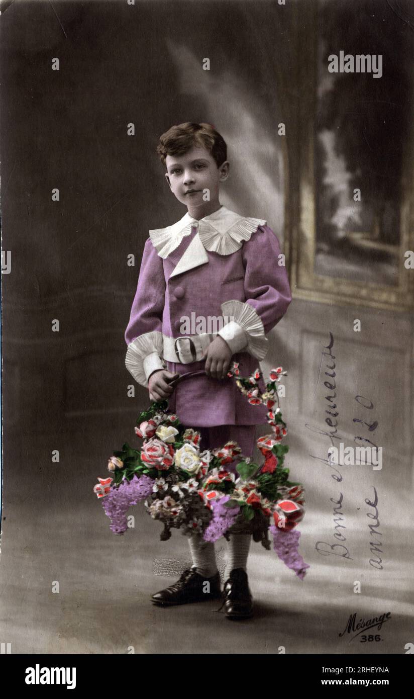 Carte de voeux de bonne annee : un enfant tenant une corde de fleurs - carte postale datee 1920 Banque D'Images