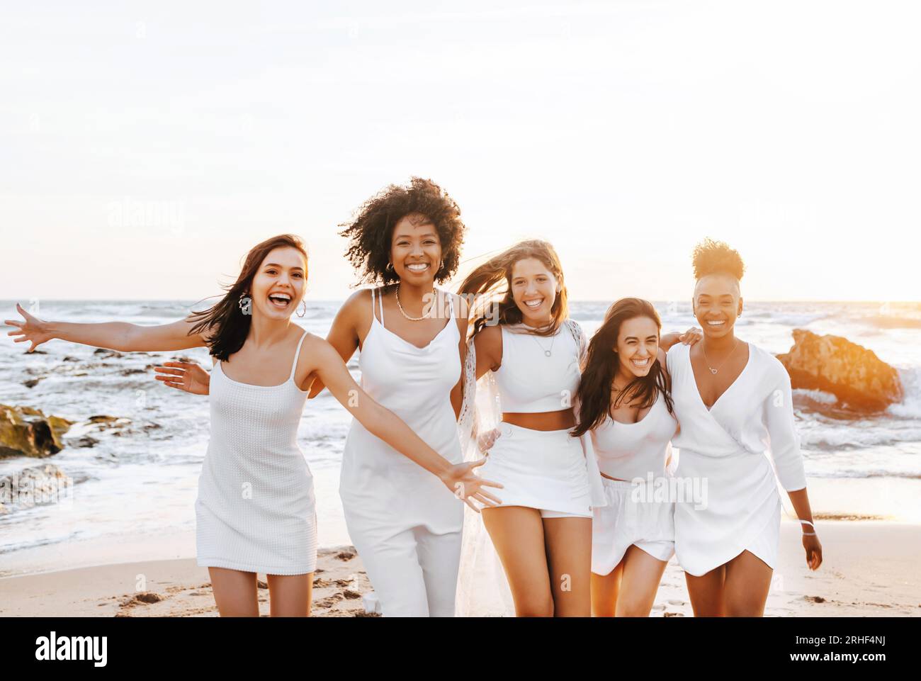 Femmes multiraciales excitées s'amusant sur la plage, souriant joyeusement tout en profitant de la fête de poule sur la côte Banque D'Images