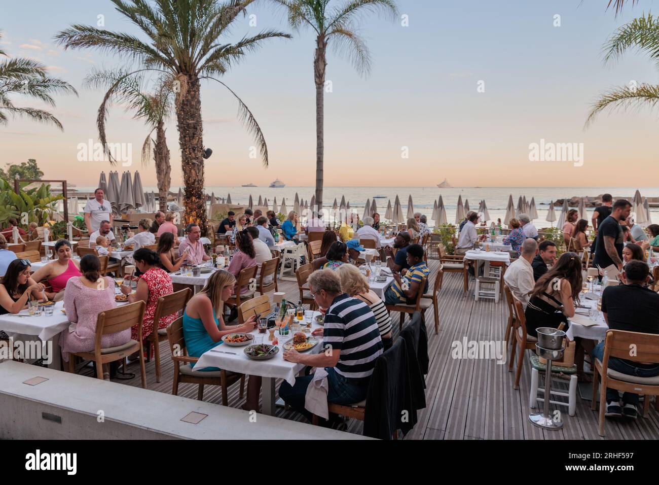 Touristes dînant dans un restaurant à côté de la plage du Larvotto à Monte Carlo Banque D'Images