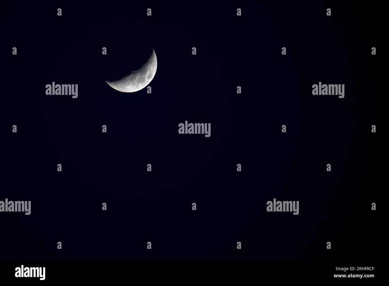 Un quart de lune brille dans un ciel nocturne d'été sans nuages. Banque D'Images