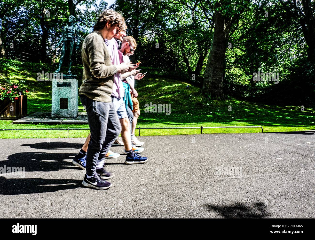Les gens regardent leurs téléphones alors qu'ils marchent à travers St Stephens Green à Dublin, en Irlande. Banque D'Images