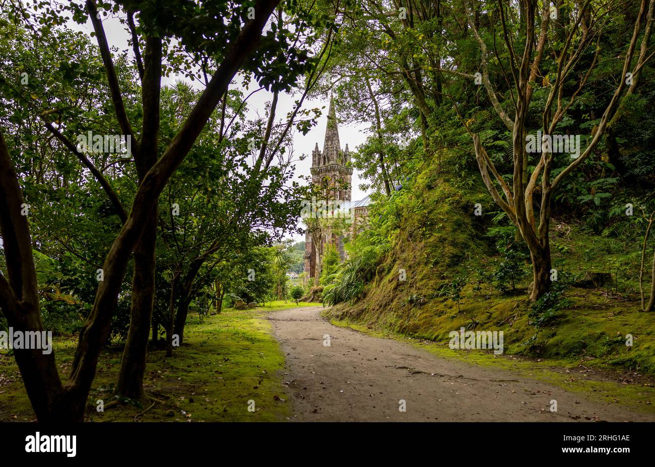 Chemin dans le jardin (Mata Jose do Canto) avec la chapelle Nossa Senhora das Vitorias en arrière-plan. Lac de Furnas. Açores, Sao Miguel Island. Banque D'Images