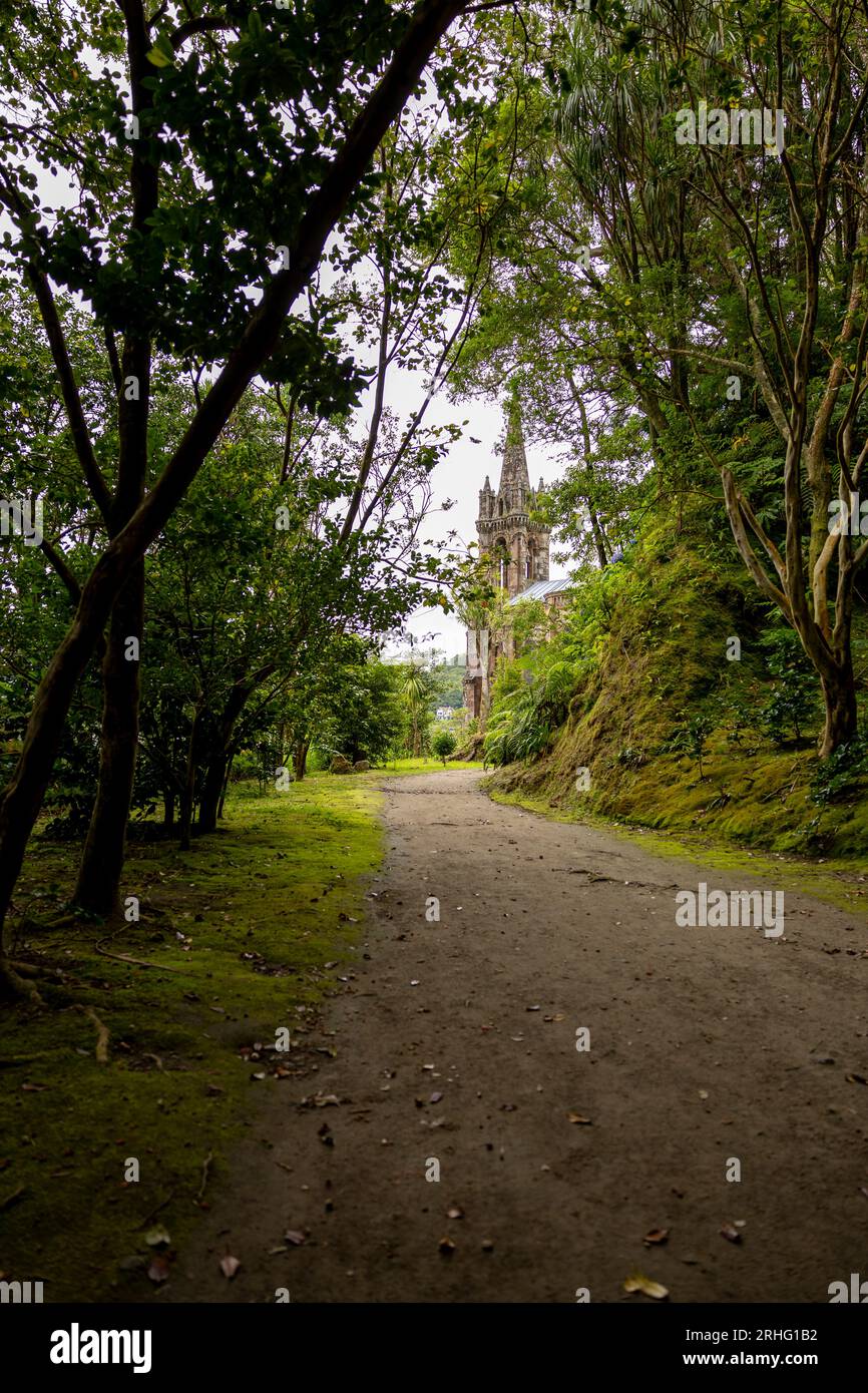 Chemin dans le jardin (Mata Jose do Canto) avec la chapelle Nossa Senhora das Vitorias en arrière-plan. Lac de Furnas. Açores, Sao Miguel Island. Banque D'Images