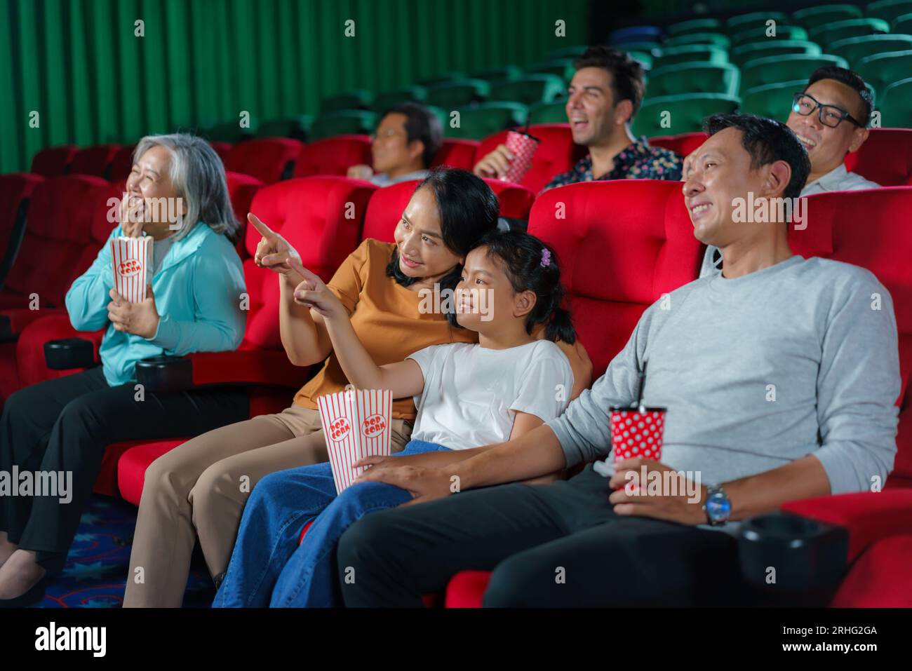 La famille asiatique heureuse de père, mère, fils et grand-mère chérit les moments du week-end au cinéma, partageant la joie et la convivialité tout en regardant une Movi Banque D'Images