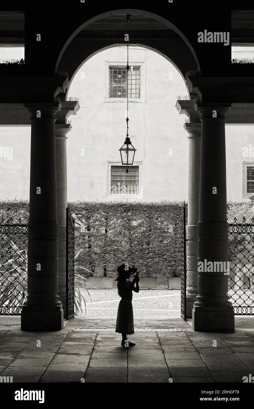 Jeune fille dans une cour romantique dans la vieille ville de Vérone en Italie prend une photo avec un smartphone Banque D'Images