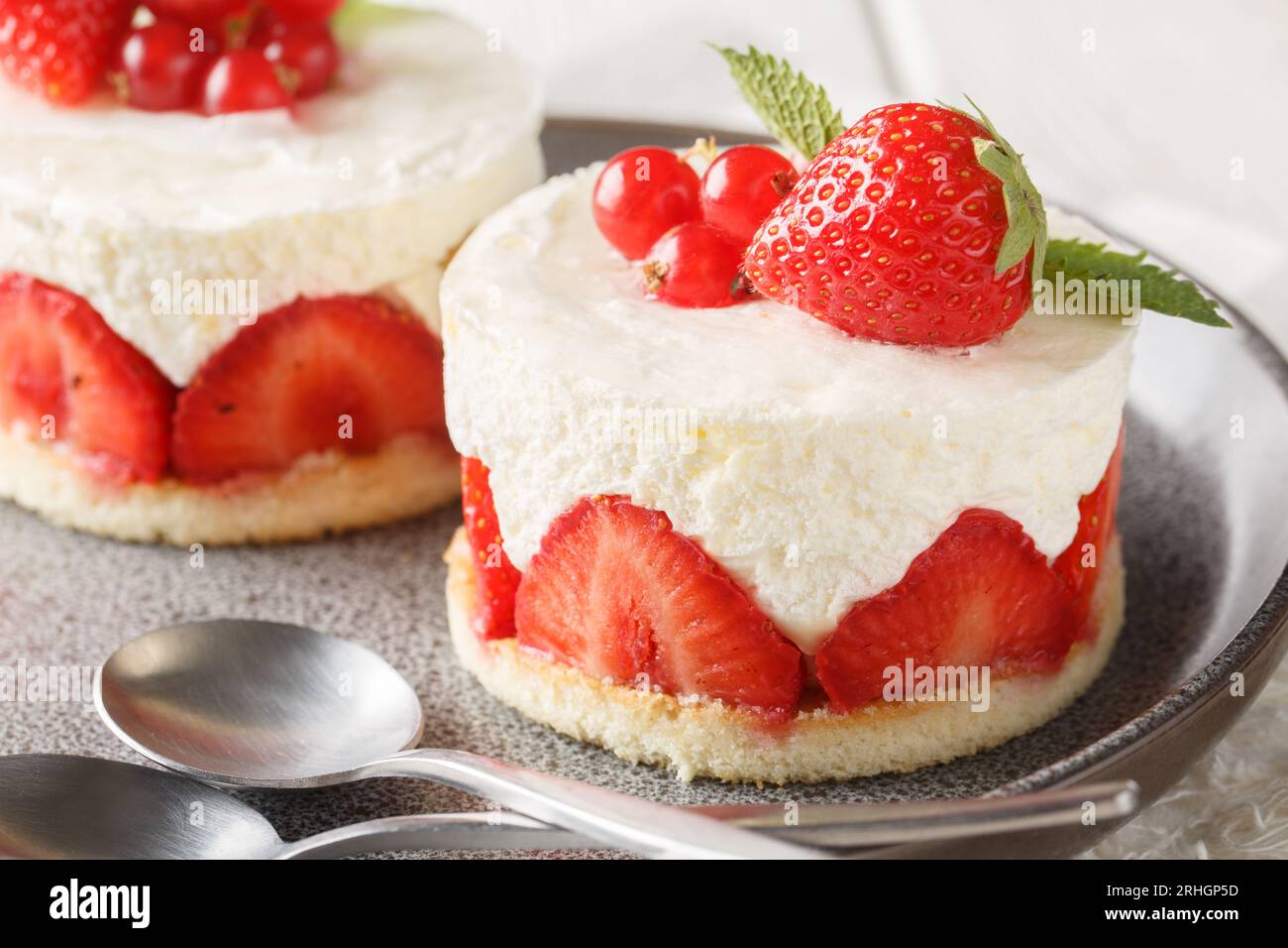 Le gâteau Fraisier à la fraise française se compose de couches d'éponge beurrées remplies de mousseline crème soyeuse closeup sur l'assiette sur la table. Horizontal Banque D'Images