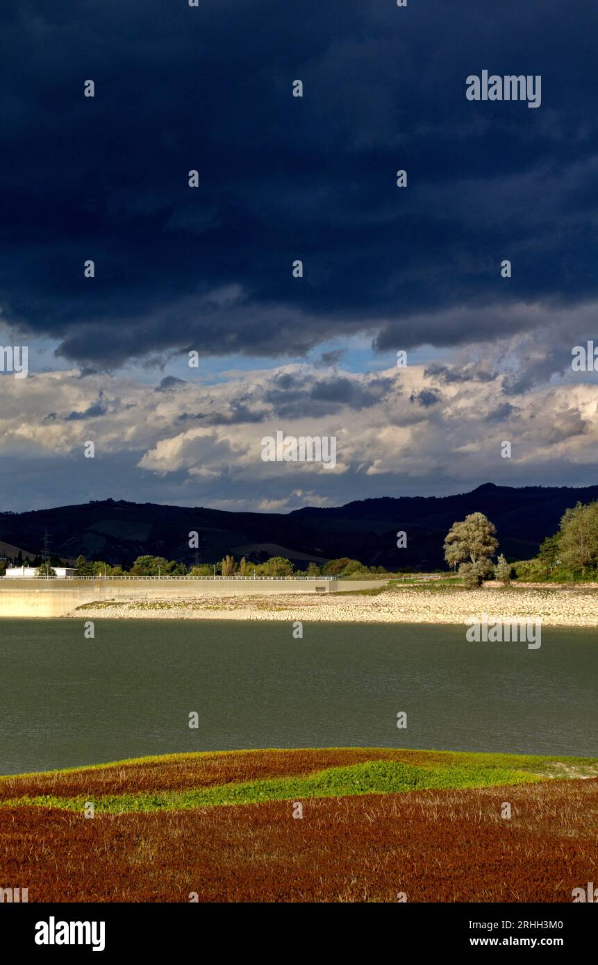 il paese di Mercatale e la diga sotto un cielo cupo autunnale Banque D'Images