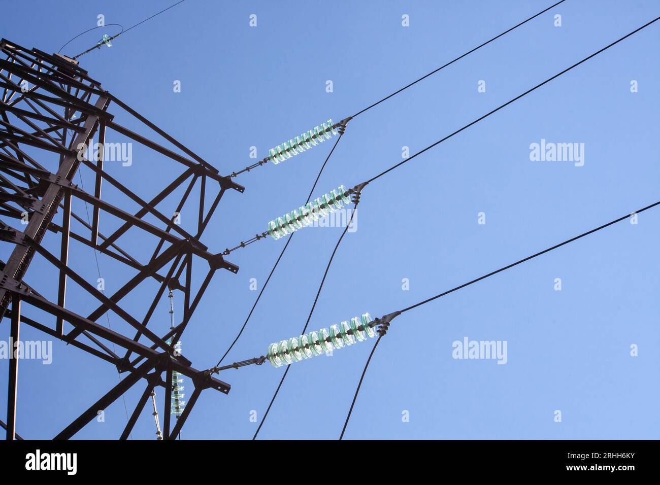 Ligne électrique d'isolant électrique de verre de haute tension contre le ciel bleu. Banque D'Images