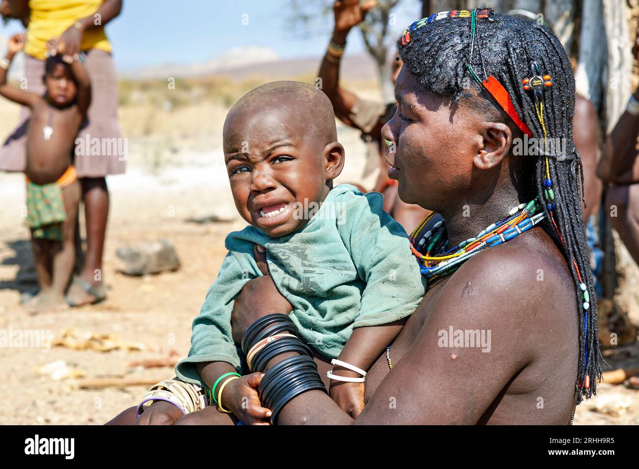 Namibie. Portrait d'une jeune femme de l'ethnie Zemba Bantu avec son enfant en pleurs, dans la région de Kunene Banque D'Images