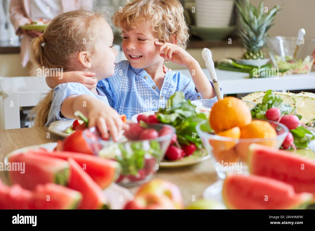 Frères et sœurs heureux avec face à face faisant de la salade dans la cuisine à la maison Banque D'Images Frères et sœurs heureux avec face à face faisant de la salade dans la cuisine à la maison Banque D'Images