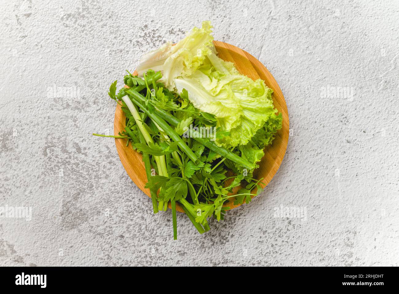 Oignons verts biologiques, ciboulette, laitue et persil sur la table en pierre Banque D'Images