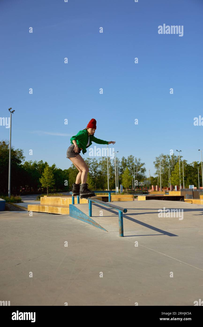 Patineuse en ligne concentrée pratiquant des cascades et des tricks sur rampe Banque D'Images