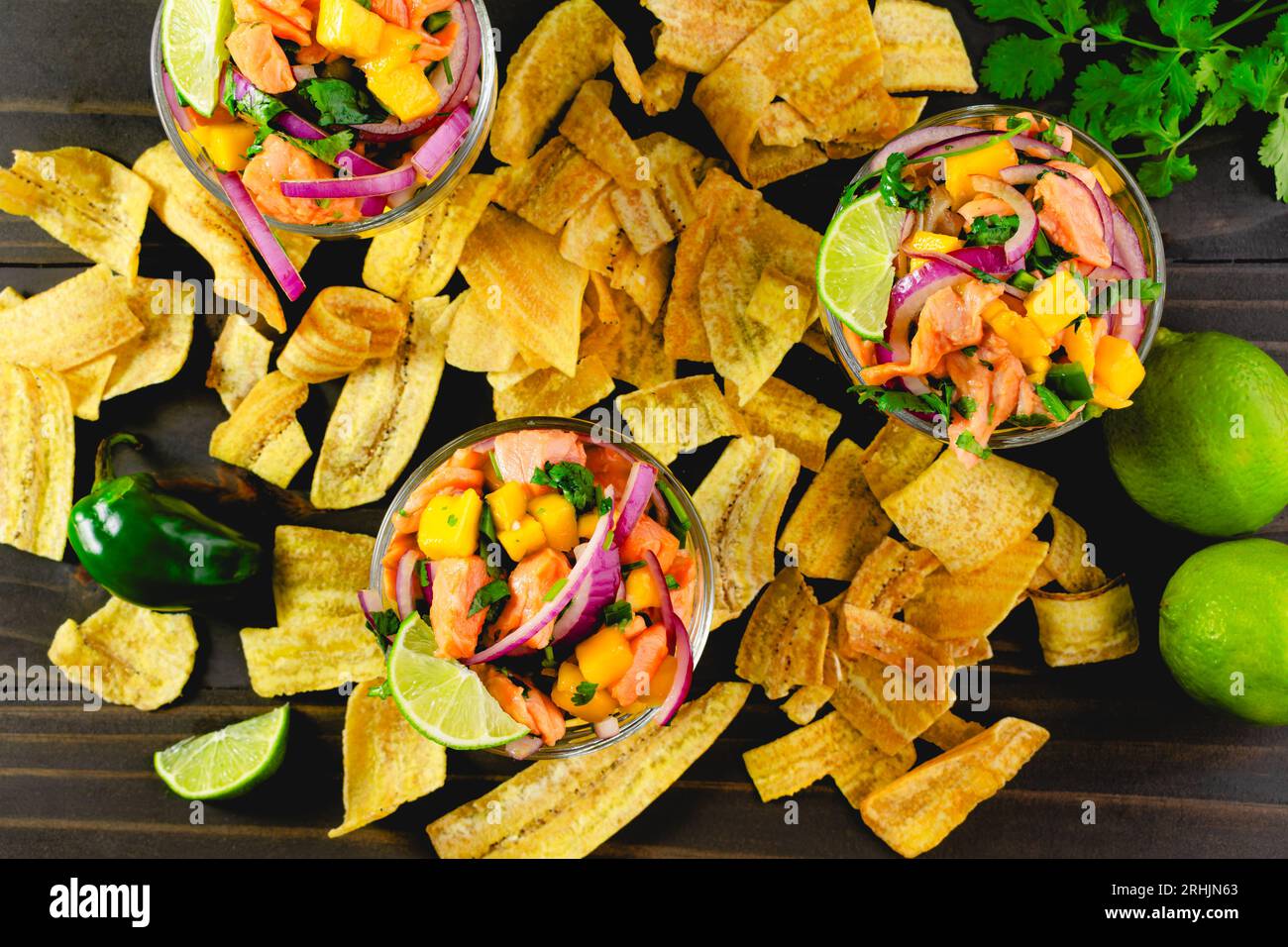 Plats de Ceviche de saumon avec mangue entouré de croustilles plantains : bols de ceviche de saumon avec des croustilles plantains et des ingrédients sur une table en bois Banque D'Images