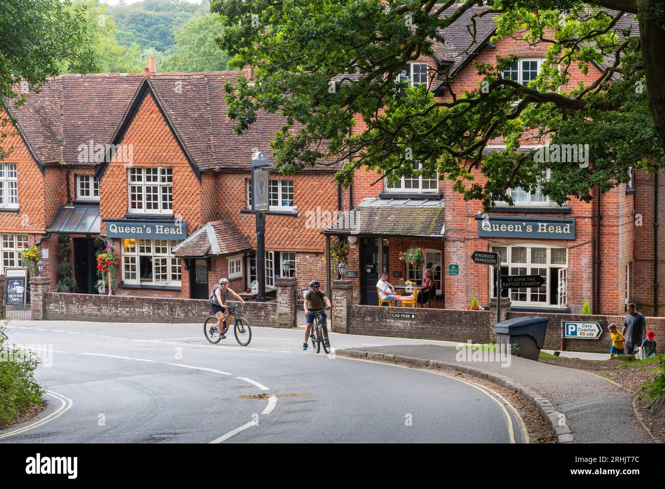 Le pub Queen's Head à Burley, un village de New Forest, Hampshire, Angleterre, Royaume-Uni, avec des gens buvant dehors, marchant et faisant du vélo Banque D'Images