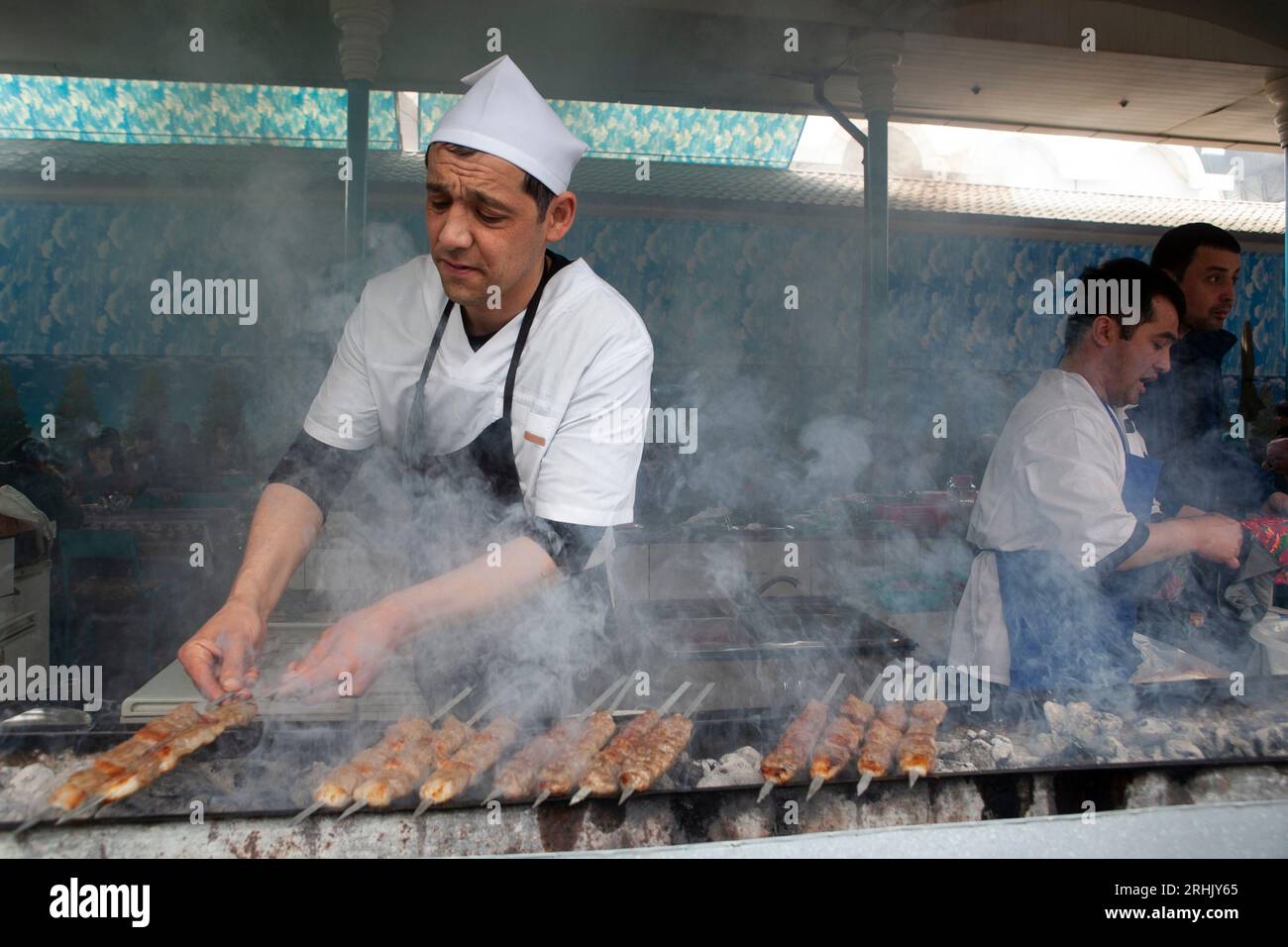 Un homme grille de la viande au bazar Chorsu à Tachkent, en Ouzbékistan. Banque D'Images