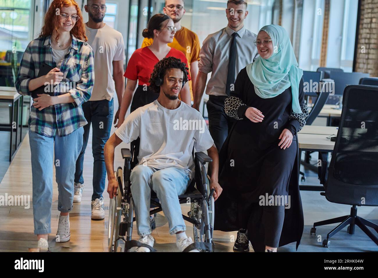 Un groupe diversifié de jeunes gens d'affaires marchant dans un couloir ...