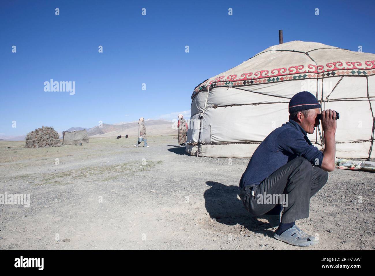 Un berger de yak dans les montagnes du Pamir au Tadjikistan utilise des jumelles pour suivre son troupeau. Banque D'Images