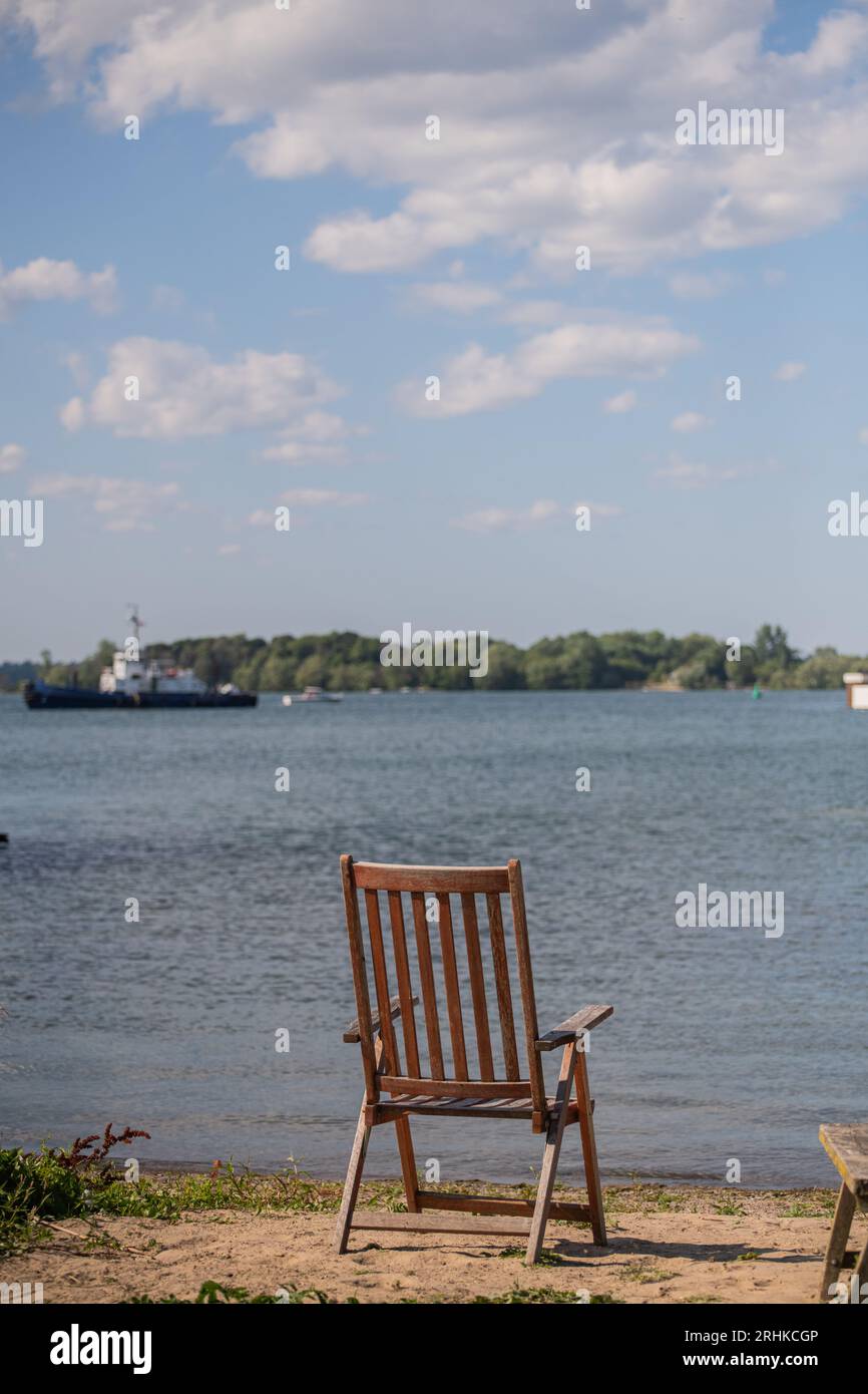 Une chaise en bois vide sur la plage surplombant le lac Ontario, signifiant des vacances reposantes au chalet et l'équilibre entre vie professionnelle et vie privée Banque D'Images