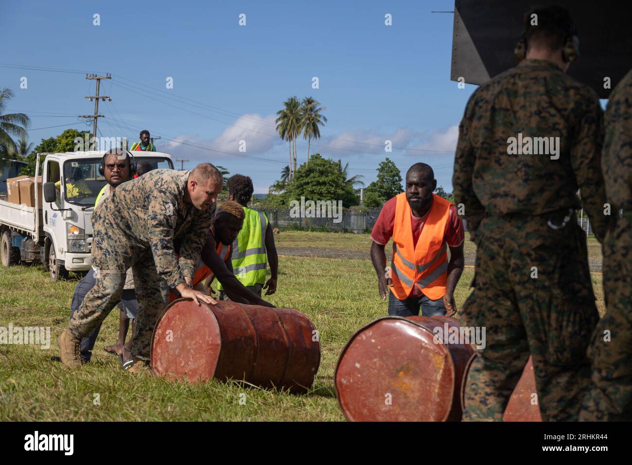 Île de Bougainville, Papouasie-Nouvelle-Guinée. 12 août 2023. Des villageois et des Marines américains roulent des barils de carburant à un avion MV-22B Osprey pour distribution dans des zones reculées à la suite des éruptions du volcan du mont Bagana, le 12 août 2023 sur l’île de Bougainville, Papouasie-Nouvelle-Guinée. Crédit : Caporal Abigail Godinez/U.S. Marines/Alamy Live News Banque D'Images