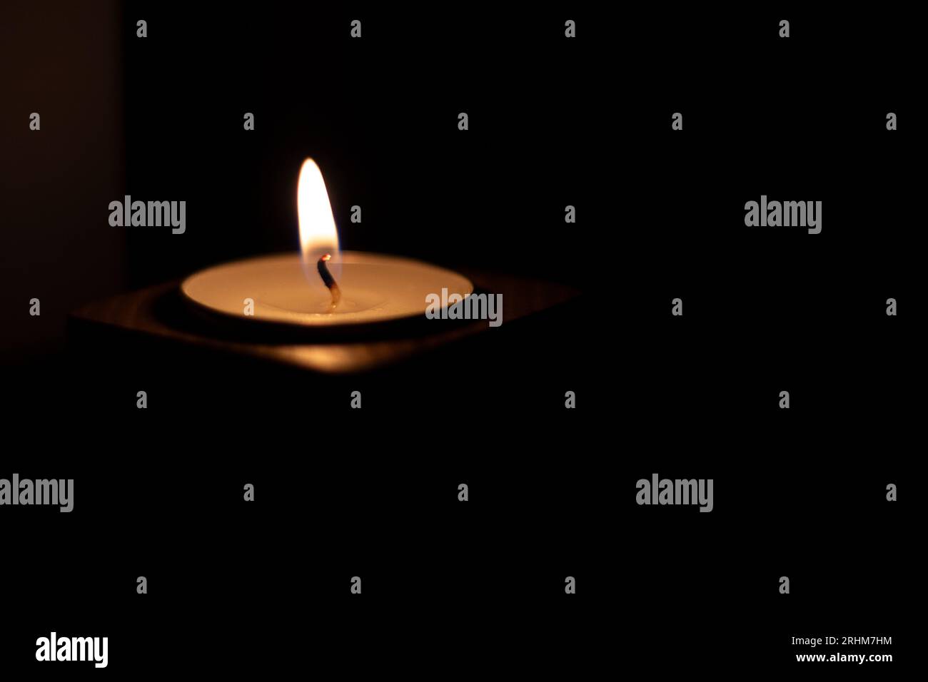 Gros plan de la flamme brûlant sur une bougie isolée sur un fond noir. Centrer Banque D'Images