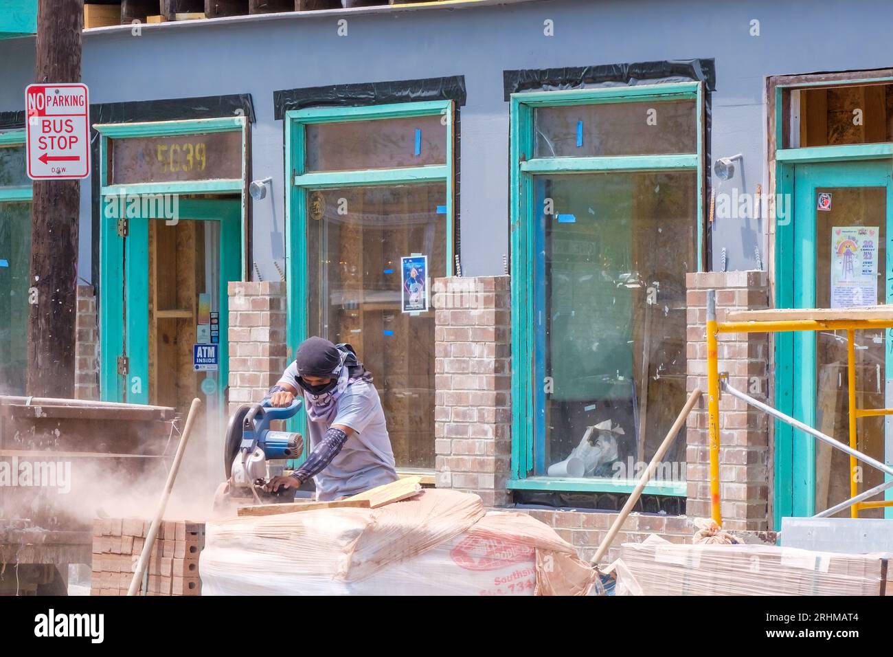 NOUVELLE-ORLÉANS, LA, USA - 16 AOÛT 2023 : ouvrier coupant des briques pour le projet de rénovation sur la façade d'une propriété commerciale sur Freret Street Banque D'Images