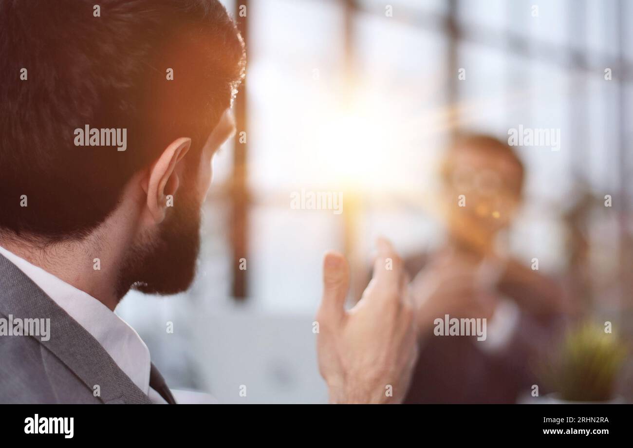 Un jeune homme est assis dos à la caméra à une table dans un bureau. Vue de l'arrière Banque D'Images