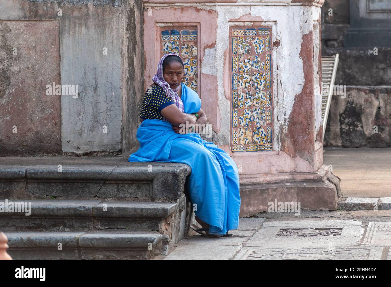 Old Goa, Inde - janvier 2023 : une travailleuse indienne portant un sari bleu qui garde un ancien site du patrimoine dans le vieux Goa. Banque D'Images