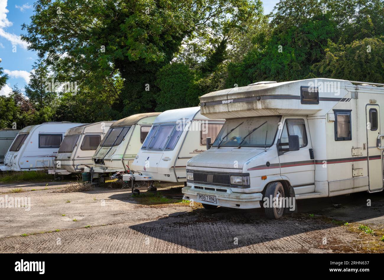 Un vieux camping-car dans une rangée de caravanes pour la plupart délabrées et sales garées à Lincoln Farm Truck Stop à Bassall Common, Solihull, West Midlands, Royaume-Uni. Banque D'Images