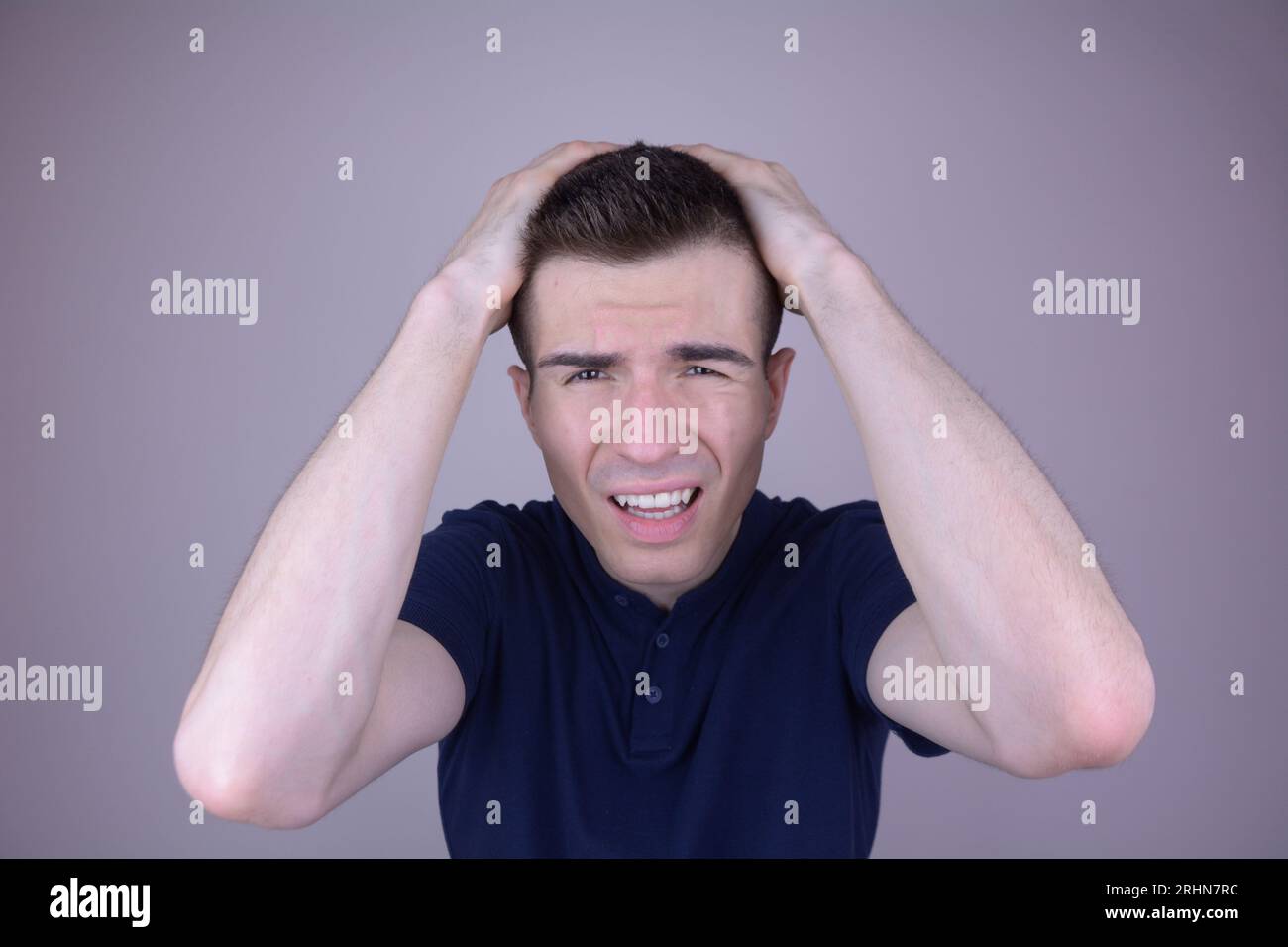 Jeune homme exprimant la douleur, tenant la tête dans les mains, concept de mal de tête sur fond isolé Banque D'Images