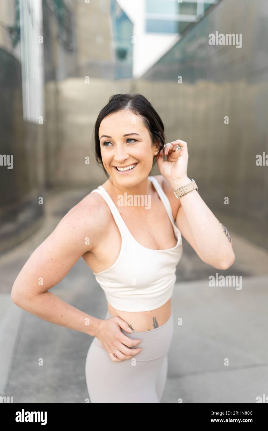 Une femme souriant et tapant ses cheveux derrière son oreille Banque D'Images