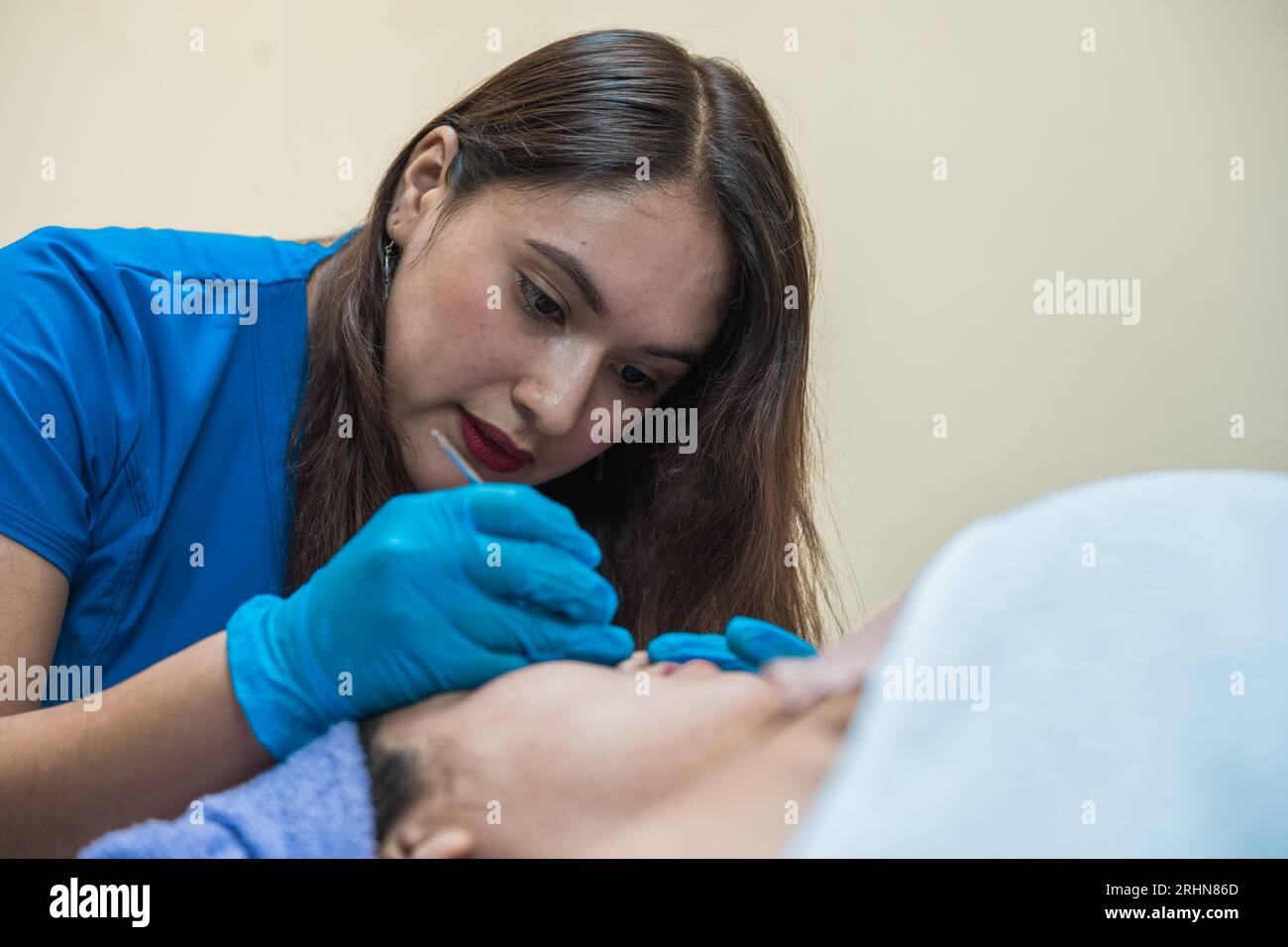 Le cosmétologue latin fait le nettoyage mécanique de la peau du visage Banque D'Images