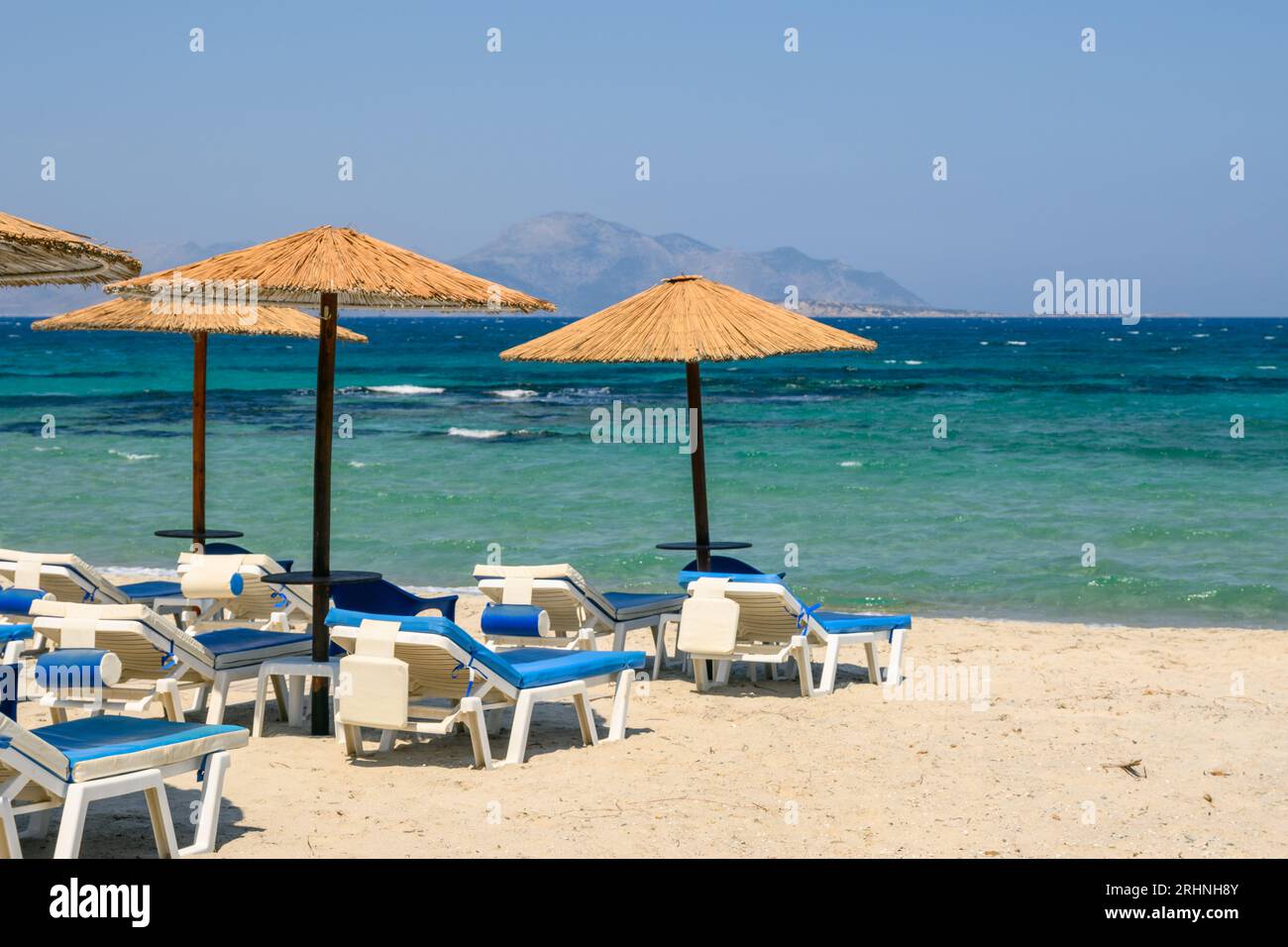 Transats avec parasol sur la plage de sable de Marmari. L'île grecque de Kos Banque D'Images